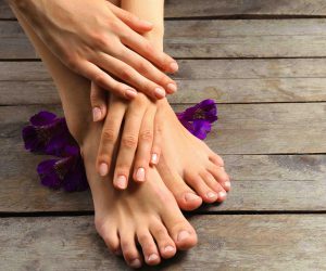 Beautifully manicured hands and feet on wooden floor - Beauchamp Foot Care