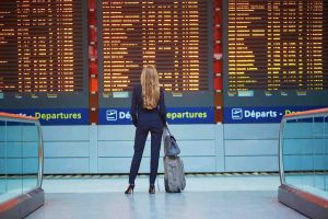 Business woman standing in front of airport destination board.